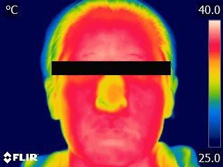 Thermal camera image of a tester's face after warming: the whole face shows red, about 38°C